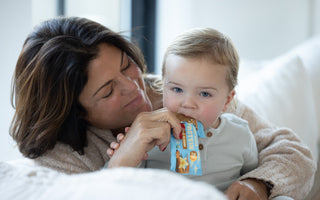 Woman feeds Healthy Truth Vanilla Protein bar to a baby on a white couch