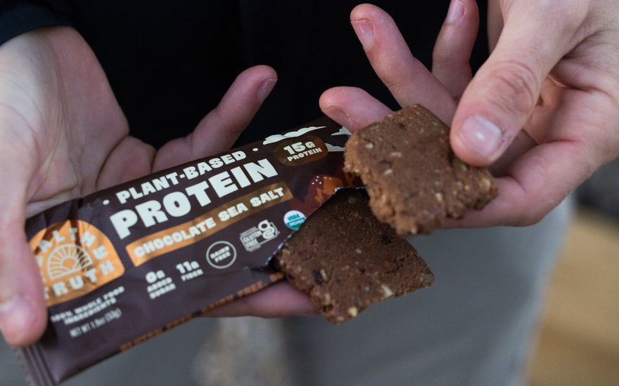 a close up of a Healthy Truth Chocolate Sea Salt Protein Bar package torn at the top to show the textured bar