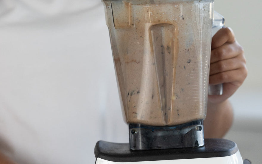 A smiling woman using a blender