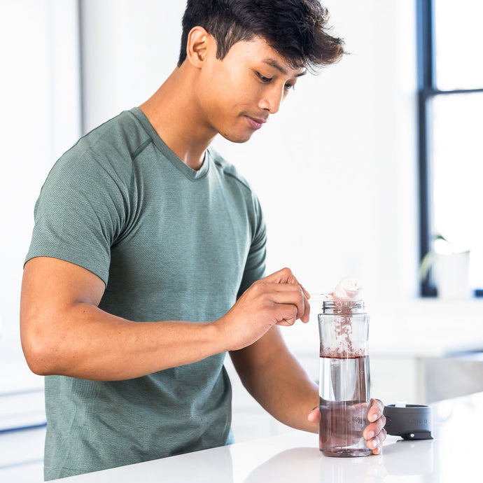 A man in athletic gear scooping powder into a water bottle