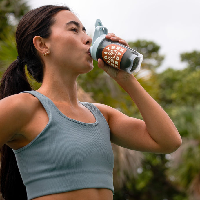 Young Woman in athletic gear drinking out of a Healthy Truth branded shaker bottle