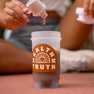 Superfood Powder being poured into a Healthy Truth labeled shaker bottle 