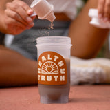 Person pouring powder into a 'HEALTHY TRUTH' shaker bottle outdoors.