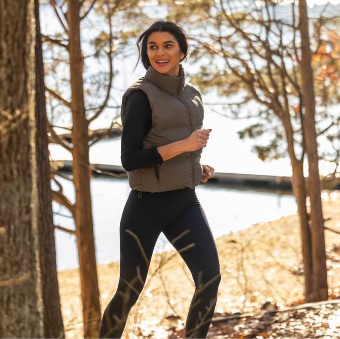 A young woman in athletic gear jogging through the woods 