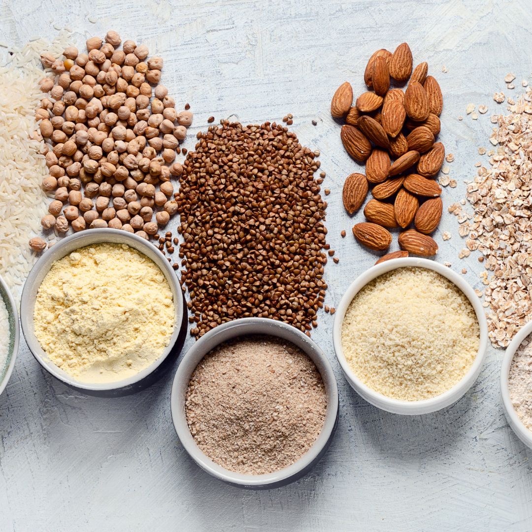 Various nuts next to bowls of blended nuts. 